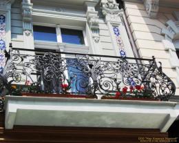 Кованое балконное ограждение вогнутой формы с коваными листьями и цветами изысканно переплитающиеся между собой №104