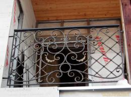 Кованое балконное ограждение. Рисунок перил выполнен в сочетании закругленных кованых элементов по центру и сетчатого узора по бокам №100